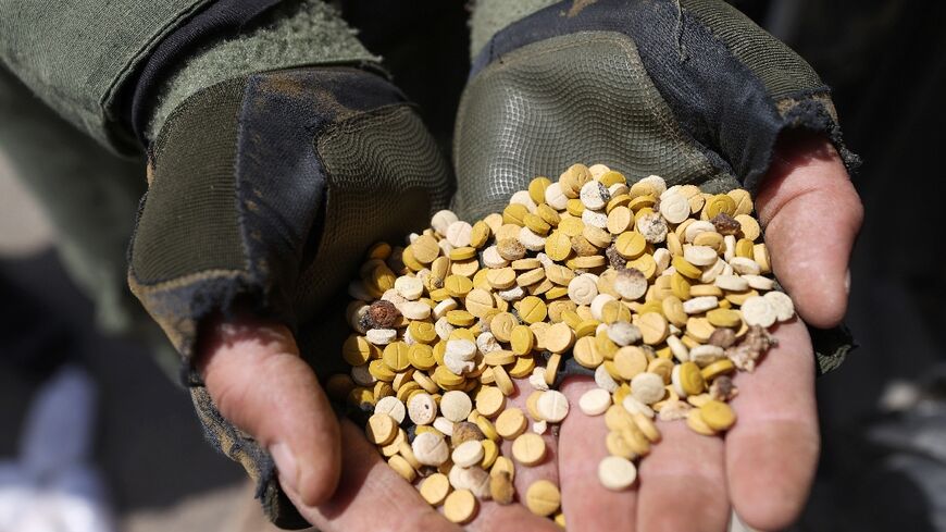 "Fighters affiliated with Syria's Hayat Tahrir al-Sham rebel group display drugs seized at a checkpoint in the countryside of the northern Aleppo province in April 2022 - OMAR HAJ KADOUR "
