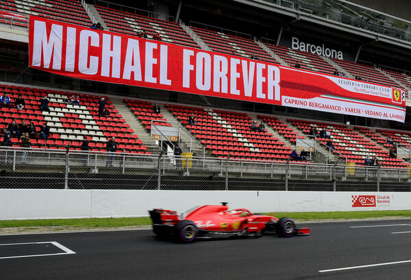 "Ferrari's German driver Sebastian Vettel drives past a tribute-banner to former German driver Michael Schumacher "