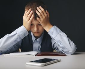 Cyberbullying concept. Stressed and upset school boy with gadget isolated.