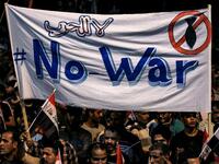 Iraqi followers of Shiite Muslim cleric Moqtada al-Sadr wave national flags and raise protest signs as they demonstrate in the capital Baghdad's central Tahrir Square late on May 24, 2019, against involvement in any conflict between Iran and the United States.  AHMAD AL-RUBAYE / AFP
