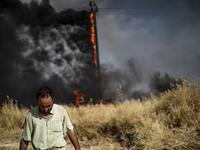 People battle a blaze next to an oil well in an agricultural field in the town of al-Qahtaniyah, in the Hasakeh province near the Syrian-Turkish border on June 10, 2019. Fires have erupted in various parts of Syria in recent weeks, with all sides blaming each other for starting them. Delil souleiman / AFP