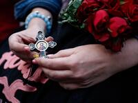 A woman holds a cross and roses as the first mass is held at the Notre-Dames de Paris Cathedral following the destructive April 15 fire, in Paris on June 15, 2019. Zakaria ABDELKAFI / AFP