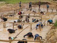 Runners crawl in the mud under barbed wire as they take part in the Mud Day, a 13km race with obstacles in Beynes, near Paris on June 16, 2019.  ALAIN JOCARD / AFP
