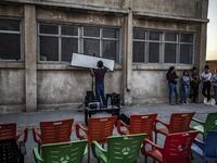 A member of Syrian-Kurdish filmmaker Shero Hinde's mobile cinema "Komina Film" initiative prepares a projector screen for a film screening for children at a school yard in the village of Shaghir Bazar, 55 kilometres southest of Qamishli in the Kurdish-populated areas of northeastern Syria's Hasakeh province, on July 28, 2019.  DELIL SOULEIMAN / AFP