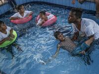  A trainer helps a Palestinian amputee child swim during a summer camp origanized by the Palestinian Children's Relief Fund (PCRF) in the town of Khan Yunis in the southern Gaza strip on August 3, 2019.  SAID KHATIB / AFP
