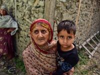 A Kashmiri woman holds a child as she looks on outside her damaged house following recently cross border shelling at the Line of Control, the de facto border between Pakistan and India, in Neelum Valley of Pakistan-administered Kashmir  SAJJAD QAYYUM / AFP