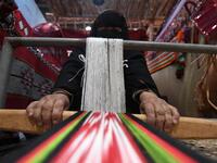 An Emirati woman works on a loom in a display of traditional crafts on the first day of the Abu Dhabi International Hunting and Equestrian exhibition (ADIHEX) in the UAE capital on August 31, 2019.  KARIM SAHIB / AFP