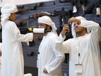 A boy poses for a picture with an assault rifle taken by another visitor on his phone during the Abu Dhabi International Hunting and Equestrian exhibition (ADIHEX) in the UAE capital Abu Dhabi on August 31, 2019.  KARIM SAHIB / AFP