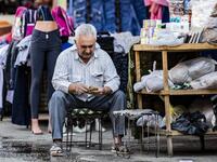 A merchant counts money in front of his shop at a market in the Kurdish-majority city of Qamishli in northeast Syria on  Delil SOULEIMAN / AFP