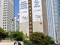 An Ultra-Orthodox Jewish man walks along a street in the Israeli coastal city of Tel Aviv on September 12, 2019, as electoral billboards are seen in the background off the facade of a building showing the faces of (L to R) Yair Lapid and retired general Benny Gantz, two of the leaders of the "Blue and White" (Kahol Lavan) electoral alliance vying for seats in the upcoming September 17 vote. Gil COHEN-MAGEN / AFP