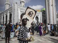 A worshipper holds a poster of Sante Serigne Touba Mbacke while waiting outside the Great Mosque of the Mourides on September 27, 2019 in Dakar, ahead of its inauguration. Senegal's influential Mouride Brotherhood will inaugurate a 30,000-capacity mosque in the capital Dakar, said to be the largest in West Africa. JOHN WESSELS / AFP