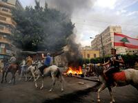 Lebanese protesters ride horses past burning tires in front of the house of former sports minister Faisal Karami, during a protest against dire economic conditions in the coastal city of Tripoli to the north of Beirut, Lebanon on October 18, 2019 Ibrahim CHALHOUB / AFP