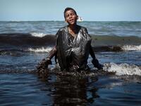 A boy walks out of the sea while removing oil spilled on Itapuama beach located in the city of Cabo de Santo Agostinho, Pernambuco state, Brazil, on October 21, 2019. LEO MALAFAIA / AFP
