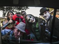 Venezuelan migrant Johnny Tales (2-R), who makes a living imitating the comicbook and film character "The Joker", performs at a street with fellow compatriots also fancy dressed as comic and film industry characters in Medellin, on October 29, 2019. JOAQUIN SARMIENTO / AFP