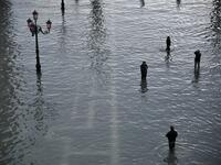 People walk across and take photos at the flooded St. Mark's Square after an exceptional overnight "Alta Acqua" high tide water level, on November 13, 2019 in Venice. Venice was hit by the highest tide in more than 50 years late November 12, with tourists wading through flooded streets to seek shelter as a fierce wind whipped up waves in St. Mark's Square. Marco Bertorello / AFP