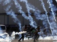 Palestinian youths run from tear gas smoke fired by Israeli security forces on November 26, 2019 during clashes in the West Bank city of Ramallah as Palestinians stage a "day of rage" against a recent US decision to no longer consider settlements in the West Bank illegal. A Palestinian convicted over the killing of three Israelis died of cancer in custody today, officials said. The death, which sparked Palestinian accusations of neglect, comes amid heightened tension with protests already scheduled in multi