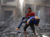 A man evacuates a young bombing casualty after a reported air strike by regime forces and their allies in the jihadist-held Syrian town of Maaret Al-Noman in the southern Idlib province, on May 26, 2019. Regime air strikes killed 12 civilians including four at a market today in a jihadist bastion in northwest Syria, a war monitor said. Abdulaziz KETAZ / AFP