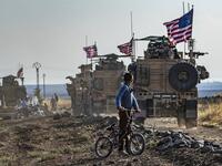 AFP PICTURES OF THE YEAR 2019 - A Syrian boy on his bicycle looks at a convoy of US armoured vehicles patrolling fields near the northeastern town of Qahtaniyah at the border with Turkey, on October 31, 2019. US forces accompanied by Kurdish fighters of the Syrian Democratic Forces (SDF) patrolled part of Syria's border with Turkey, in the first such move since Washington withdrew troops from the area earlier this month, an AFP correspondent reported. Delil SOULEIMAN / AFP