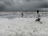 Residents play over foamy discharge, caused by pollutants, as it mixes with the surf at Marina beach in Chennai on December 1, 2019. Arun SANKAR / AFP