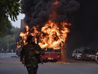 A man walks on a street as a bus is on fire following a demonstration against the Indian government's Citizenship Amendment Bill (CAB) in New Delhi on December 15, 2019. Angry protesters in northeast India vowed on December 15 to keep demonstrating against a contentious citizenship law as the death toll from bloody clashes opposing the bill rose to six. STR / AFP
