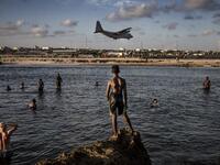Soldiers enjoying a day off and Somali people look from the beach at a military plane landing within Mogadishu’s airport base in Mogadishu, Somalia, on December 13, 2019. LUIS TATO / AFP