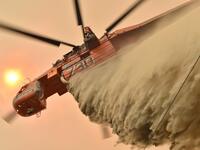 A helicopter drops fire retardent to protect a property in Balmoral, 150 kilometres southwest of Sydney on December 19, 2019. A state of emergency was declared in Australia's most populated region on December 19, as a record heat wave fanned unprecedented bushfires. PETER PARKS / AFP