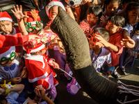 An elephant dressed in a Santa Claus costume presents gifts to schoolchildren during Christmas celebrations in Ayutthaya on December 23, 2019. Wearing red and white hats and a string of bells, Thai elephants passed out Christmas gifts to hundreds of schoolchildren on Monday despite growing criticism over using the animals in performances. The annual festive event is organised by a nearby elephant park, whose mahouts or handlers started in the early morning dressing the animals. Thailand is largely Buddhist 