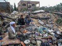 Palestinian Hammouda Abu Amra, 51, (L) sits with his sons on the site of his destroyed home in Khan Yunis in the southern Gaza Strip on January 10, 2020. Abu Amra, whose house was destroyed by an Israeli air strike last November, now lives in a shack with his family of seventeen. SAID KHATIB / AFP
