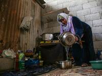 The wife of Palestinian Hammouda Abu Amra, Naama, prepares food in a shack in Khan Yunis in the southern Gaza Strip on January 10, 2020. Abu Amra, whose house was destroyed by an Israeli air strike last November, now lives in a shack with his family of seventeen. SAID KHATIB / AFP