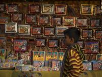A young Hindu devotee walks past a stall selling religious images during the Gangasagar Mela, at Sagar Island, some 150 kilometres south of Kolkata on January 14, 2020. XAVIER GALIANA / AFP