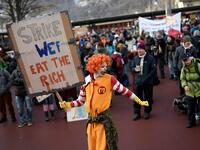 A man dressed as Ronald McDonald, the clown character used as the primary mascot of the McDonald's fast-food restaurant chain, holds a placard as he takes part in a gathering called by climate activists prior to the start of a march to Davos ahead of the World Economic Forum in January 19, 2020 in Landquart. FABRICE COFFRINI / AFP