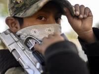 A boy looks on as he holds a gun as the Regional Coordinator of Community Authorities (CRAC-PF) community police force teaches a group of children how to use weapons, at a basketball court in the village of Ayahualtempan, Guerrero State, Mexico, on January 24, 2020. The CRAC-PF vigilante group trains children as young as five so they can protect themselves from drug-related criminal groups operating in the area. AFP