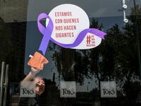 A woman cleans the glass door of a Mexico City restaurant with a sign reading 'We stand with those who make us giants' during Monday's 'A Day Without Us' protest (AFP)