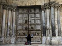 A woman prays in front of the Church of the Holy Sepulchre in the Old City of Jerusalem following the closure of the city for non-residents as a measure to contain the spread of the novel coronavirus, on March 30, 2020. MENAHEM KAHANA / AFP