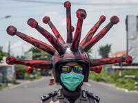 An Indonesian police officer wearing a Covid-19 coronavirus themed helmet conducts a campaign and disinfects motorists' vehicles in Mojokerto, East Java on April 3, 2020. Juni Kriswanto / AFP