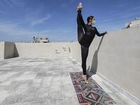 Sherazade Mami, a 28-year-old Tunisian professional dancer and performer at the Caracalla dance theatre and a teacher at the Caracalla dance school, practices while wearing a surgical mask on the roof of her apartment building in the suburb of Dekwaneh on the eastern outskirts of Lebanon's capital Beirut on April 4, 2020. Due to the confinement regulations imposed to combat the COVID-19 coronavirus pandemic, Mami opted to continue practicing on her rooftop to remain in shape. JOSEPH EID / AFP