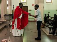 Father Kennedy Mugute, the Vicar General of the Archdiocese of Harare, gives communion to the head of media Ronald Mapfumo (R), as he conducts a Palm Sunday mass, which is livestreamed to parishioners on Facebook, in the empty Cathedral of the Sacred Heart in Harare, on April 5, 2020, on the seventh day of a lockdown in Zimbabwe. AFP
