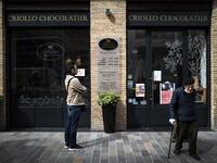 A client leaves Criollo chocolate maker shop after buying Easter chocolates as another one waits outside to respect the rules of social distancing in shops on April 7, 2020 in Toulouse, southern France, on the twenty-second day of a strict lockdown in France to stop the spread of COVID-19, caused by the novel coronavirus. Lionel BONAVENTURE / AFP