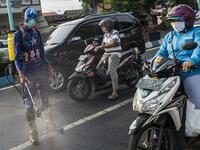 An Indonesian police officer wearing a superhero costume on the street disinfects motorists' vehicles in Pasuruan, East Java on April 9, 2020, amid concert to the COVID-19 coronavirus. JUNI KRISWANTO / AFP
