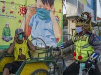 An Indonesian police officer wearing an Indonesian superhero costume on the street gives a face mask to a man in Pasuruan, East Java on April 9, 2020, amid concert to the COVID-19 coronavirus. JUNI KRISWANTO / AFP