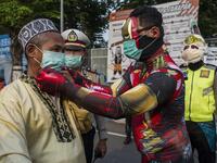 Indonesian police officers wearing Indonesian superhero costumes on the street adjusts a face mask in Pasuruan, East Java on April 9, 2020, amid concert to the COVID-19 coronavirus. JUNI KRISWANTO / AFP