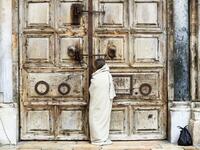 A Christian pilgrim dressed as Jesus Christ stands in front of the closed door of the Holy Sepulchre Church in Jerusalem's Old City on April 10, 2020, marking Good Friday, amid the COVID-19 pandemic crisis. All cultural sites in the Holy Land are shuttered, regardless of their religious affiliation, as authorities seek to forestall the spread of the deadly respiratory disease, which will prevent Christians from congregating for the Easter service, this coming Sunday for Catholic worshippers, then a week lat