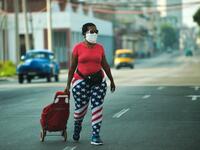 A woman wearing tights depicting the US flag and a face mask, walks along a street in Havana, on April 13, 2020. While Cuba tries to stop the spread of the coronavirus on the island, with 726 cases, voices can be heard to demand the lifting of the US embargo to facilitate the arrival of medical products. YAMIL LAGE / AFP