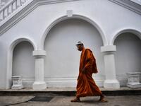 A novice monk wearing a face shield as a preventive measure against the spread of the COVID-19 coronavirus walks through Wat Molilokkayaram Buddhist temple in Bangkok on April 20, 2020. Lillian SUWANRUMPHA / AFP