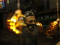 A Palestinian worker at a desserts shop wipes the surface of its window while clad in a face mask, a precaution due to the COVID-19 coronavirus pandemic, in Rafah in the southern Gaza Strip on the second night of the Muslim holy month of Ramadan early on April 25, 2020, as people shop for supplies at the start of the holy month. SAID KHATIB / AFP