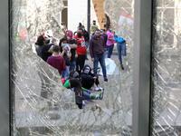Lebanese anti-government protesters, some wearing protective masks amid the COVID-19 pandemic, are seen through a broken store window during a demonstration against the growing economic hardship in downtown Beirut on May 1, 2020, marking International Workers' Day (Labour Day). ANWAR AMRO / AFP