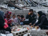 This picture taken on May 4, 2020 during the Muslim holy fasting month of Ramadan shows Tareq Abu Ziad (L), a displaced Syrian from the town of Ariha in the southern countryside of the Idlib province, smoking as members of his family break their fast together for the sunset "iftar" meal, in the midst of the rubble of their destroyed home upon their return to the town for one day after fleeing during the previous military assault by Syrian government forces and their allies. AAREF WATAD / AFP