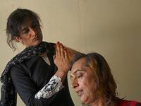 In this picture taken on May 10, 2020, Julie Khan (L), a member of the transgender community, cuts the hair of Nadeem Kashish at a shelter house in the Bari Imam neighbourhood of Islamabad. Transgender people in the country are known as "khawajasiras" or "hijras" -- an umbrella term denoting a third sex that includes transgender women and cross-dressers. Pakistan became one of the first countries in the world to legally recognise a third sex in 2009 and began issuing transgender passports from 2017. Aamir Q