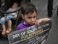 A young child holds a poster as he joins refugees participating in a rally in Athens on June 20, 2020, marking World Refugee Day aS THEY demand rights and housing for refugees and migrants in Greece. Louisa GOULIAMAKI / AFP