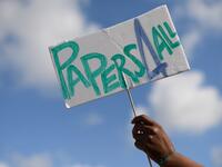 A woman holds a placard reading "Papers for all" during a migrant´s demonstration in Barcelona on June 20, 2020, marking World Refugee Day and demanding legal papers for refugees and migrants in Spain. Josep LAGO / AFP